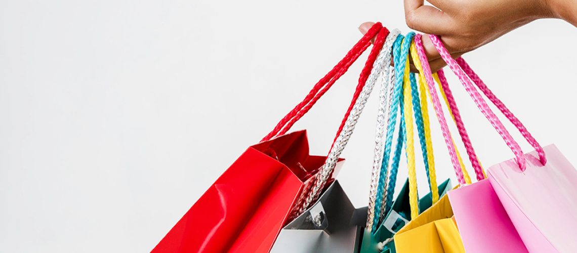 mano che tiene shopping bag di diversi colori